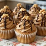 Freshly baked Chunky Monkey Cupcakes topped with frosting and nuts.